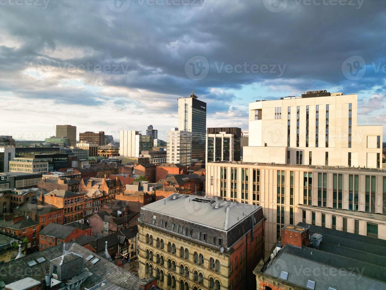 Aerial View of Greater Manchester City Centre and Tall Buildings During Golden Hour of Sunset. England UK. High Angle Footage Was Captured with Drone's Camera During Windy day of May 5th, 2024 photo
