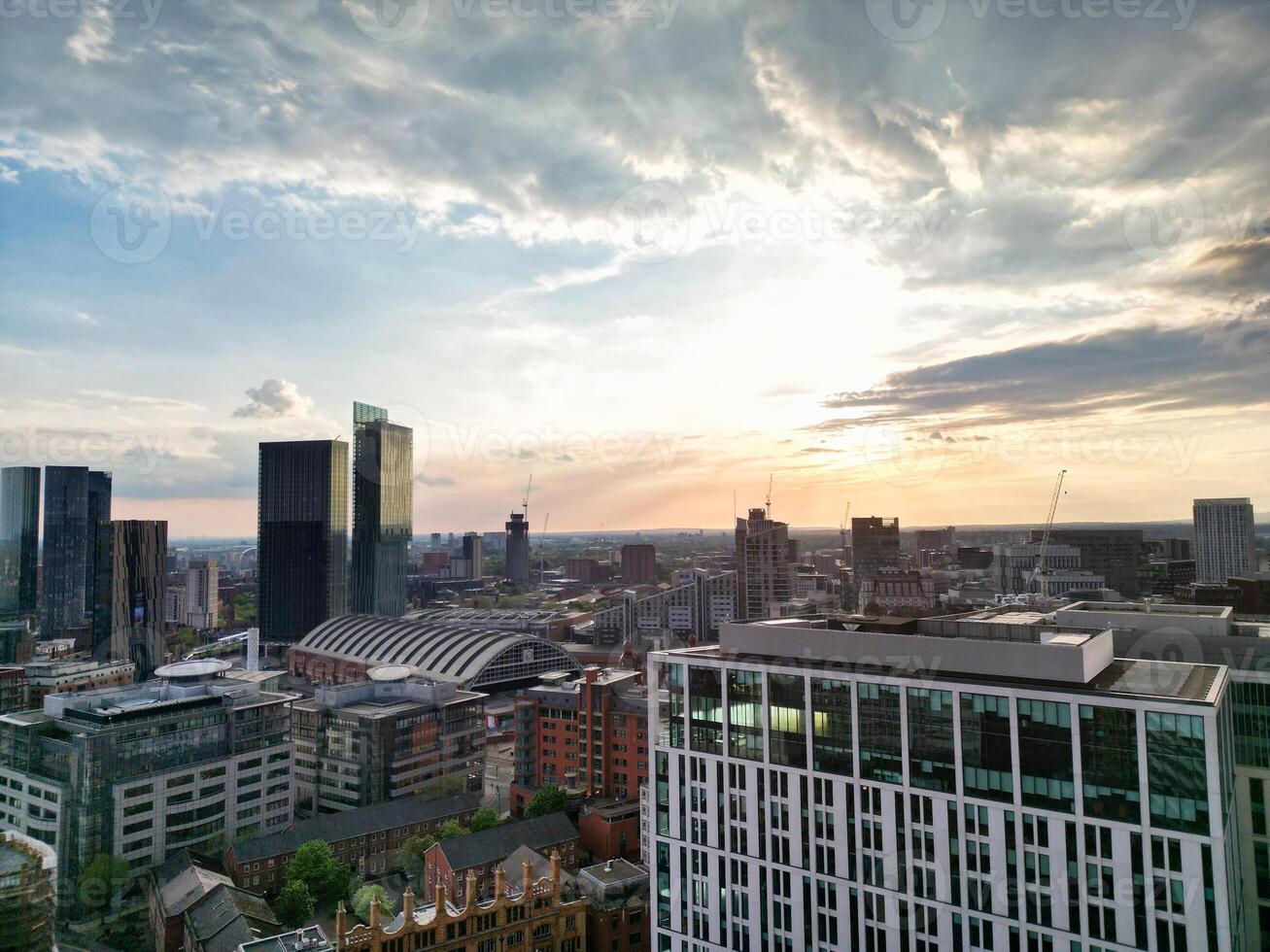 Aerial View of Greater Manchester City Centre and Tall Buildings During Golden Hour of Sunset. England UK. High Angle Footage Was Captured with Drone's Camera During Windy day of May 5th, 2024 photo