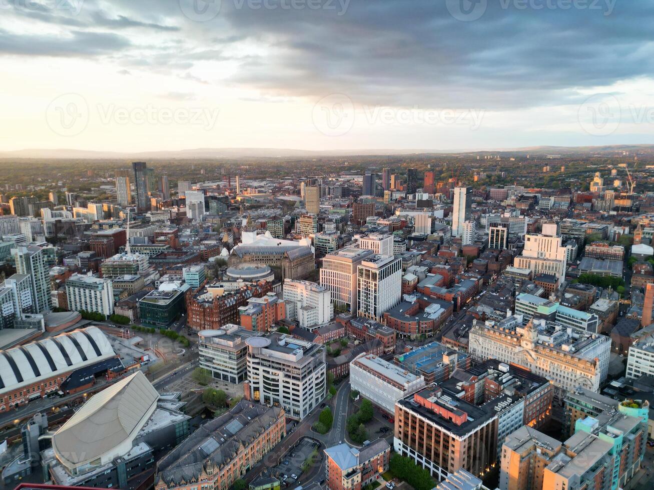 Aerial View of Greater Manchester City Centre and Tall Buildings During Golden Hour of Sunset. England UK. High Angle Footage Was Captured with Drone's Camera During Windy day of May 5th, 2024 photo