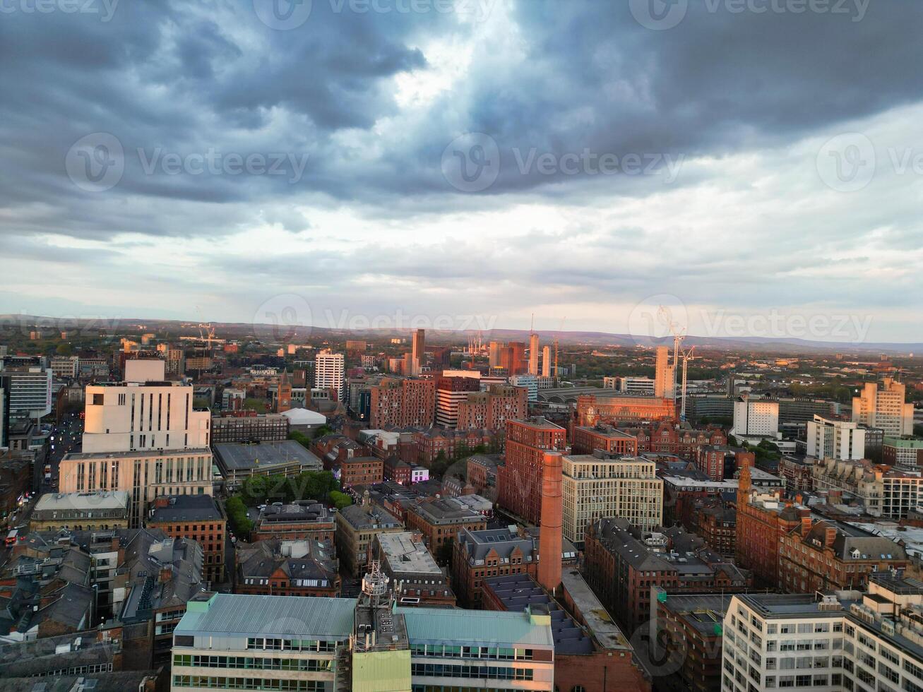 Aerial View of Greater Manchester City Centre and Tall Buildings During Golden Hour of Sunset. England UK. High Angle Footage Was Captured with Drone's Camera During Windy day of May 5th, 2024 photo