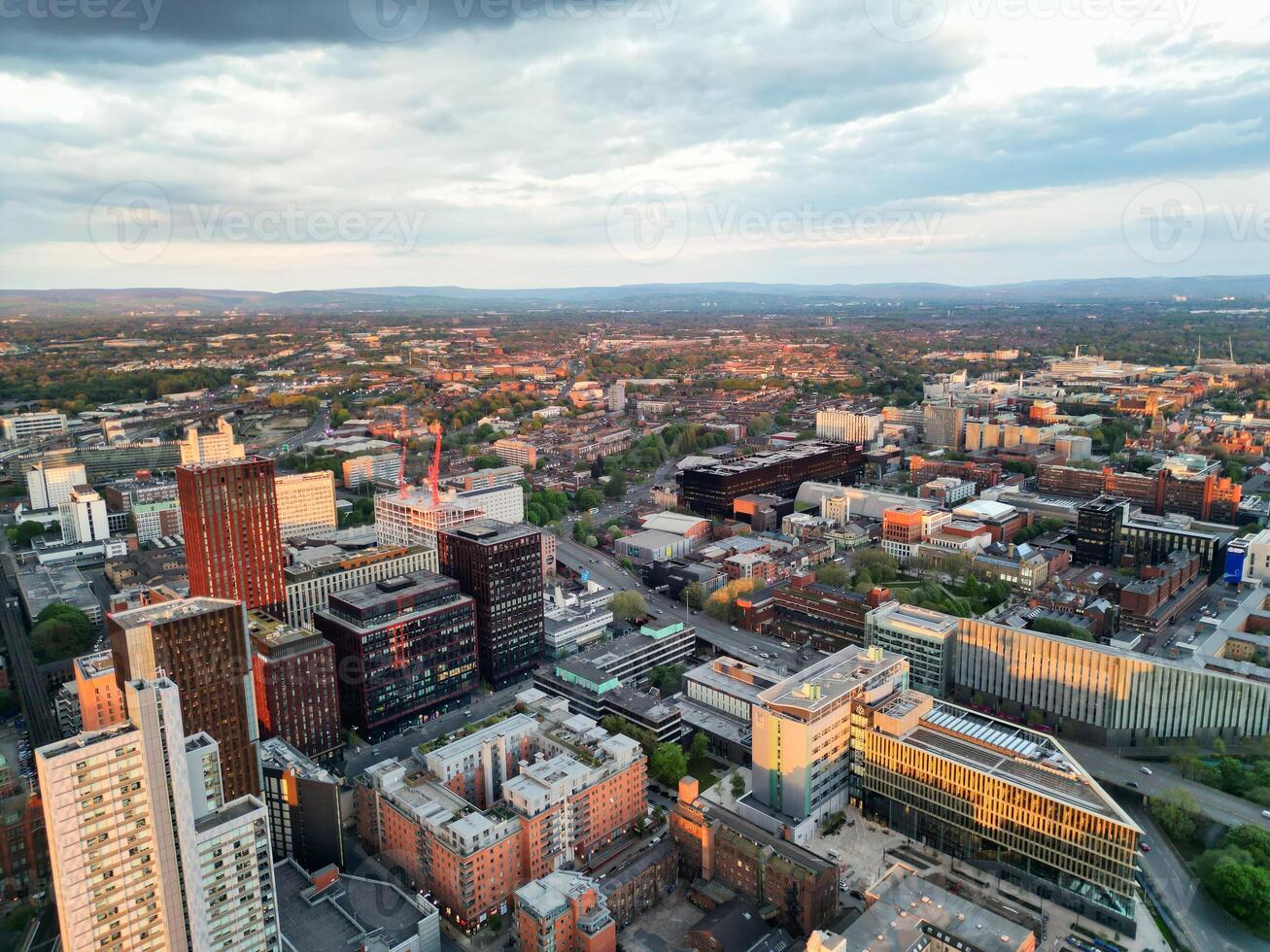 Aerial View of Greater Manchester City Centre and Tall Buildings During Golden Hour of Sunset. England UK. High Angle Footage Was Captured with Drone's Camera During Windy day of May 5th, 2024 photo