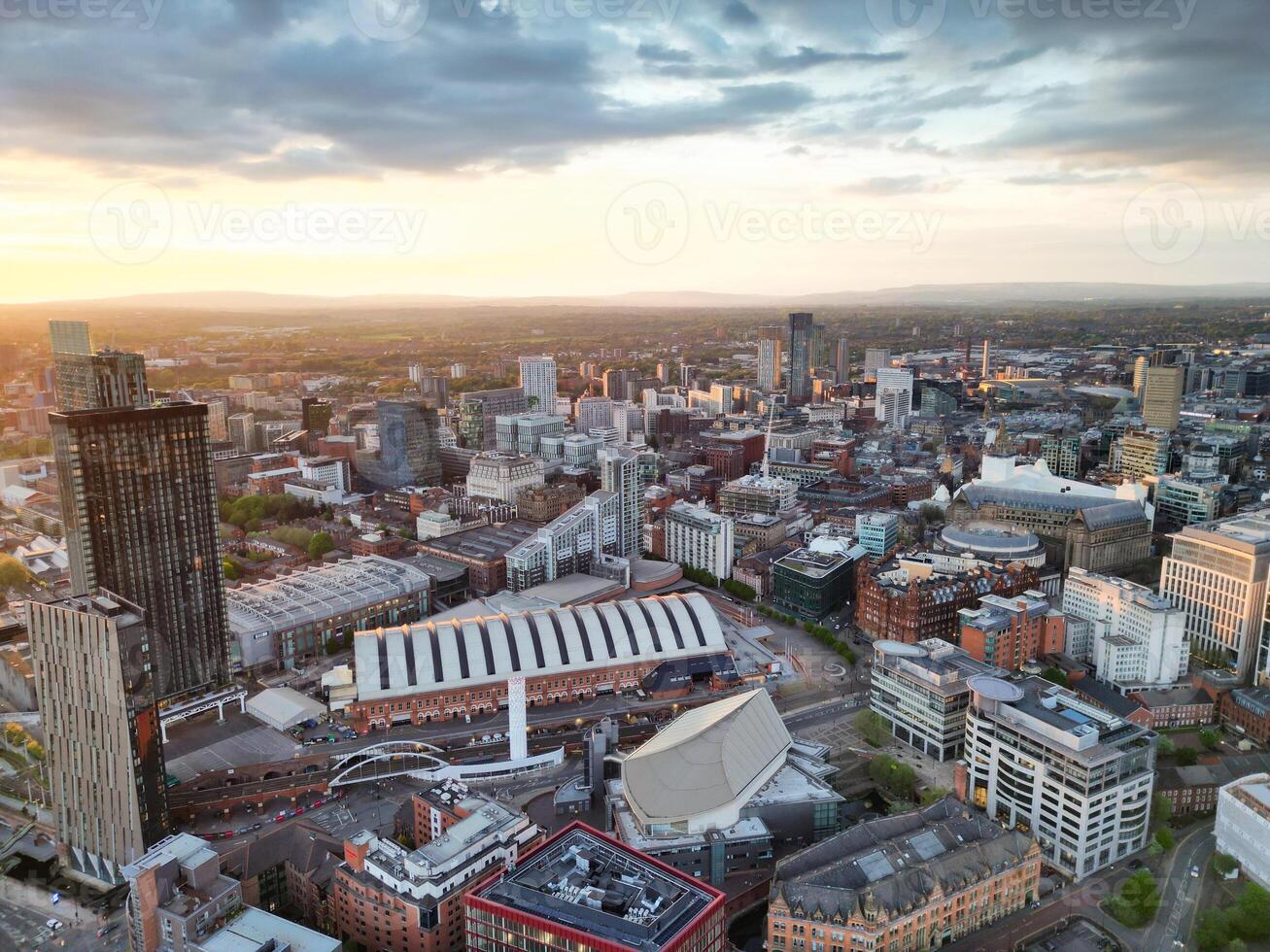 Aerial View of Greater Manchester City Centre and Tall Buildings During Golden Hour of Sunset. England UK. High Angle Footage Was Captured with Drone's Camera During Windy day of May 5th, 2024 photo