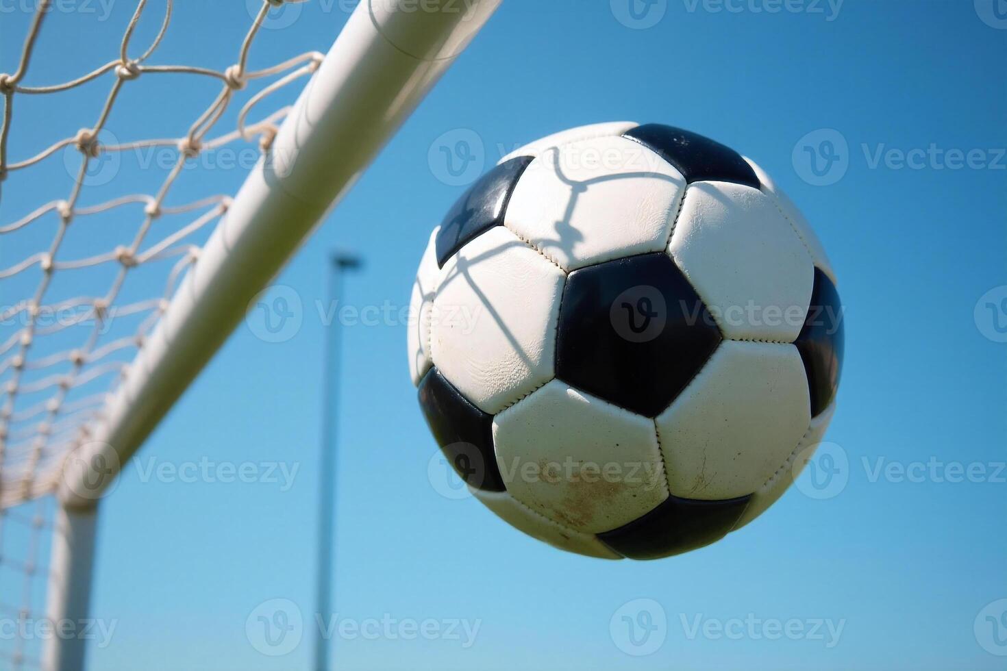 Soccer Ball Flying into Goal Net Against Blue Sky photo