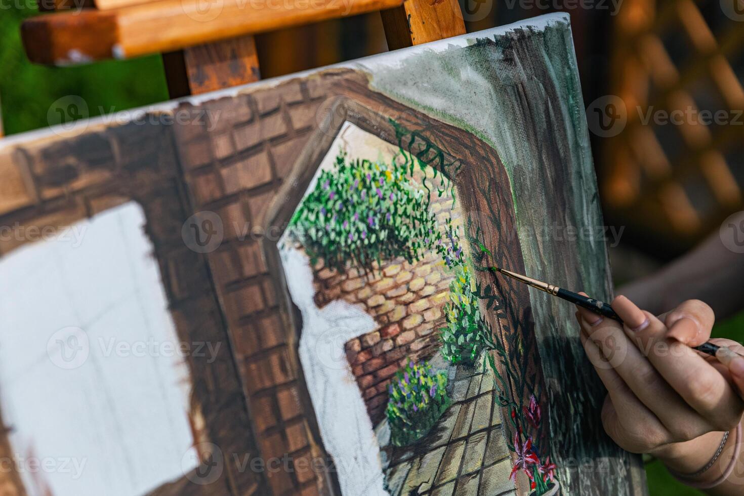 Close-up of someone skillfully painting on a canvas. The artwork looks like it depicts a rustic scene, possibly featuring elements like bricks or wood, giving it a cozy, homely feel. photo