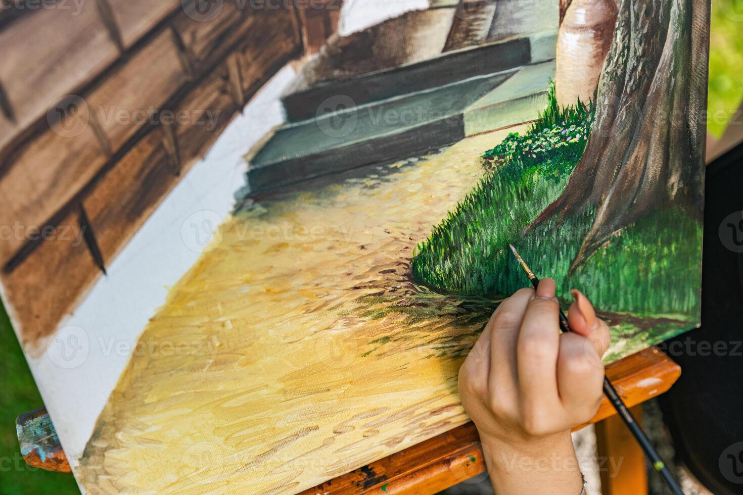 Close-up of someone skillfully painting on a canvas. The artwork looks like it depicts a rustic scene, possibly featuring elements like bricks or wood, giving it a cozy, homely feel. photo