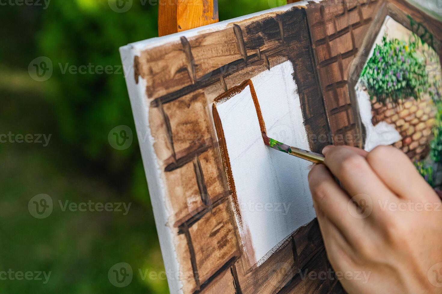 Close-up of someone skillfully painting on a canvas. The artwork looks like it depicts a rustic scene, possibly featuring elements like bricks or wood, giving it a cozy, homely feel. photo