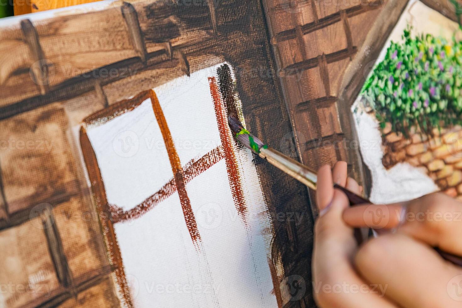 Close-up of someone skillfully painting on a canvas. The artwork looks like it depicts a rustic scene, possibly featuring elements like bricks or wood, giving it a cozy, homely feel. photo