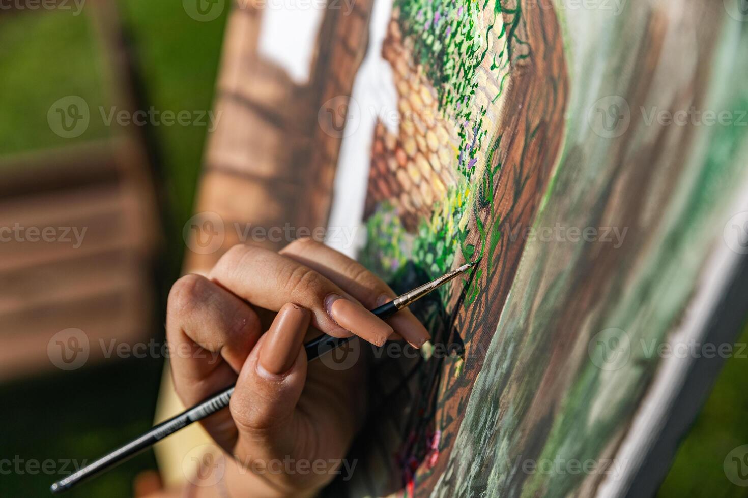 Close-up of someone skillfully painting on a canvas. The artwork looks like it depicts a rustic scene, possibly featuring elements like bricks or wood, giving it a cozy, homely feel. photo