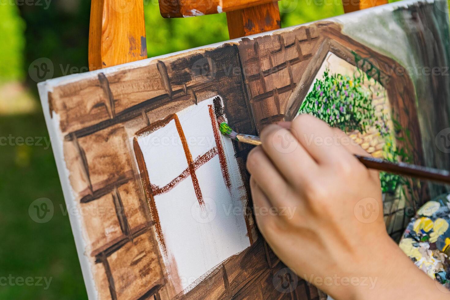 Close-up of someone skillfully painting on a canvas. The artwork looks like it depicts a rustic scene, possibly featuring elements like bricks or wood, giving it a cozy, homely feel. photo