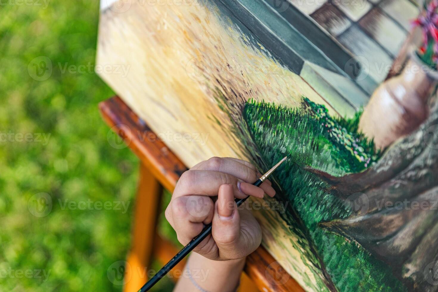 Close-up of someone skillfully painting on a canvas. The artwork looks like it depicts a rustic scene, possibly featuring elements like bricks or wood, giving it a cozy, homely feel. photo