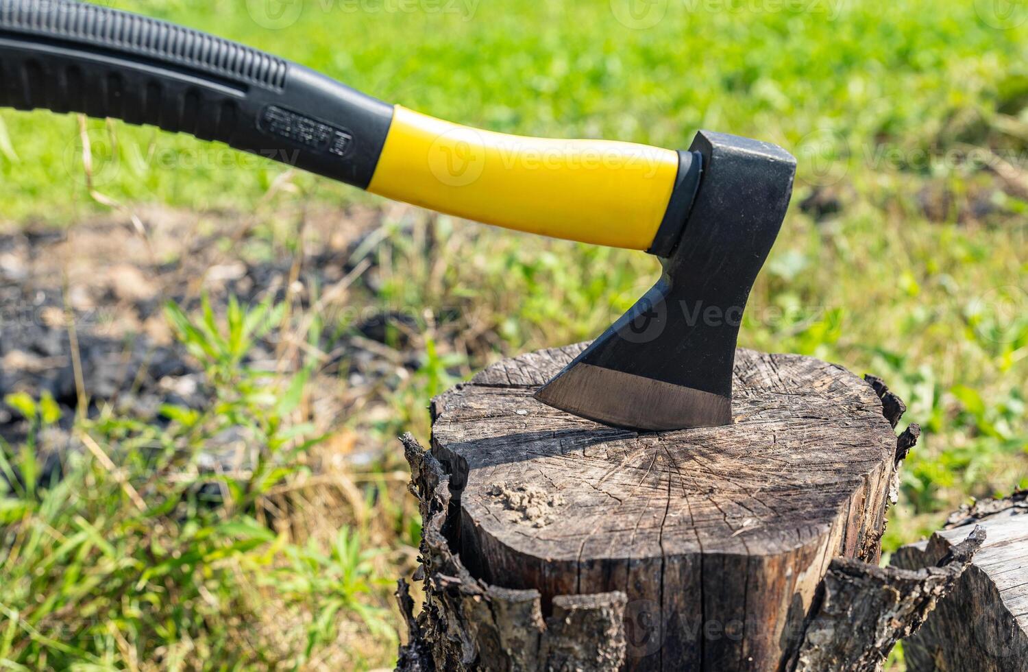 A small, rather heavy ax stuck in a stump for chopping wood. Close-up photograph of an axe stuck in a wooden tree stump, illustrating themes of nature, the outdoors, and woodworking. photo