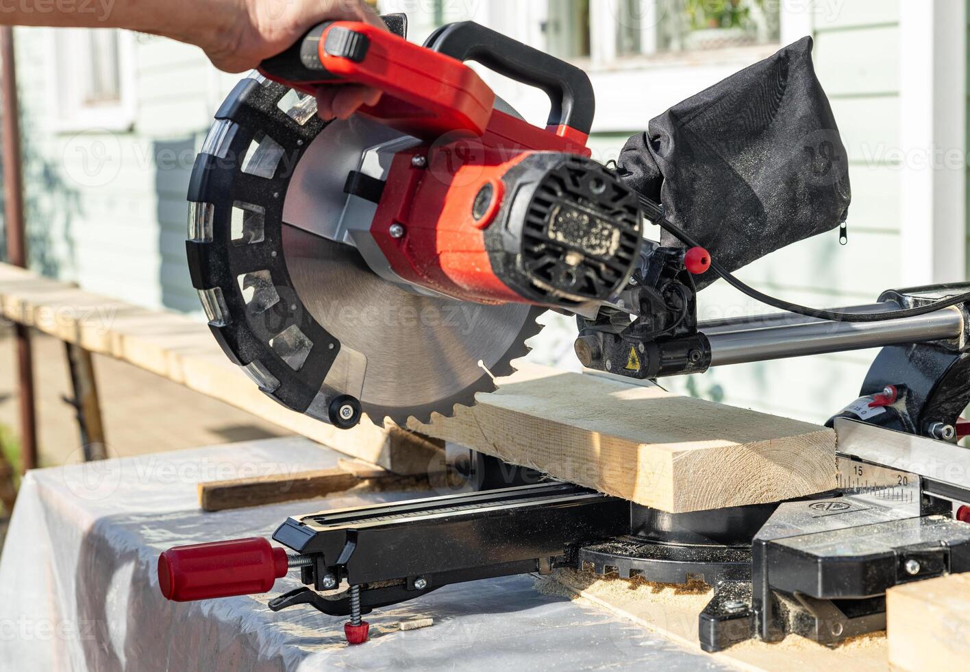 Cuts a wooden beam using a circular saw. Home furniture workshop. Work in his carpentry workshop. Miter saw and planks for building a house. photo