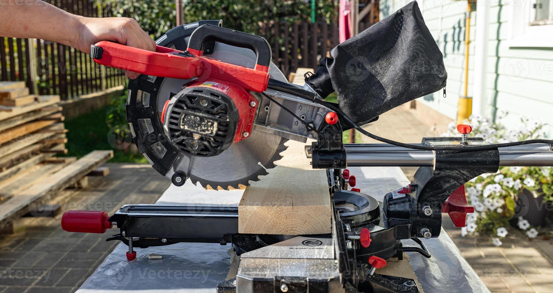 Cuts a wooden beam using a circular saw. Home furniture workshop. Work in his carpentry workshop. Miter saw and planks for building a house. photo