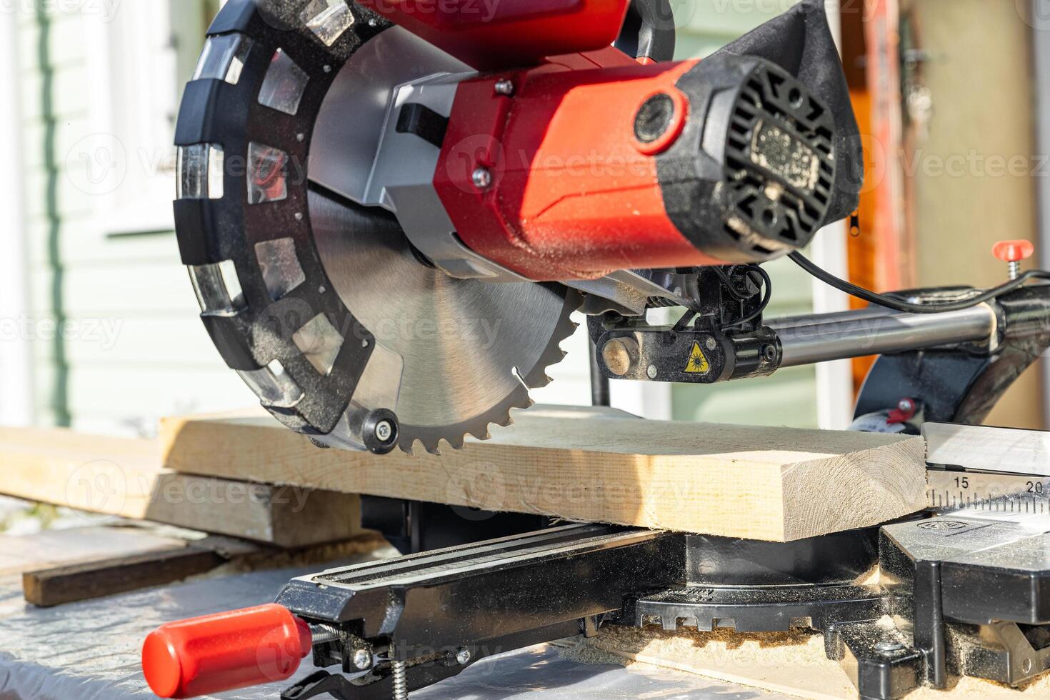Cuts a wooden beam using a circular saw. Home furniture workshop. Work in his carpentry workshop. Miter saw and planks for building a house. photo