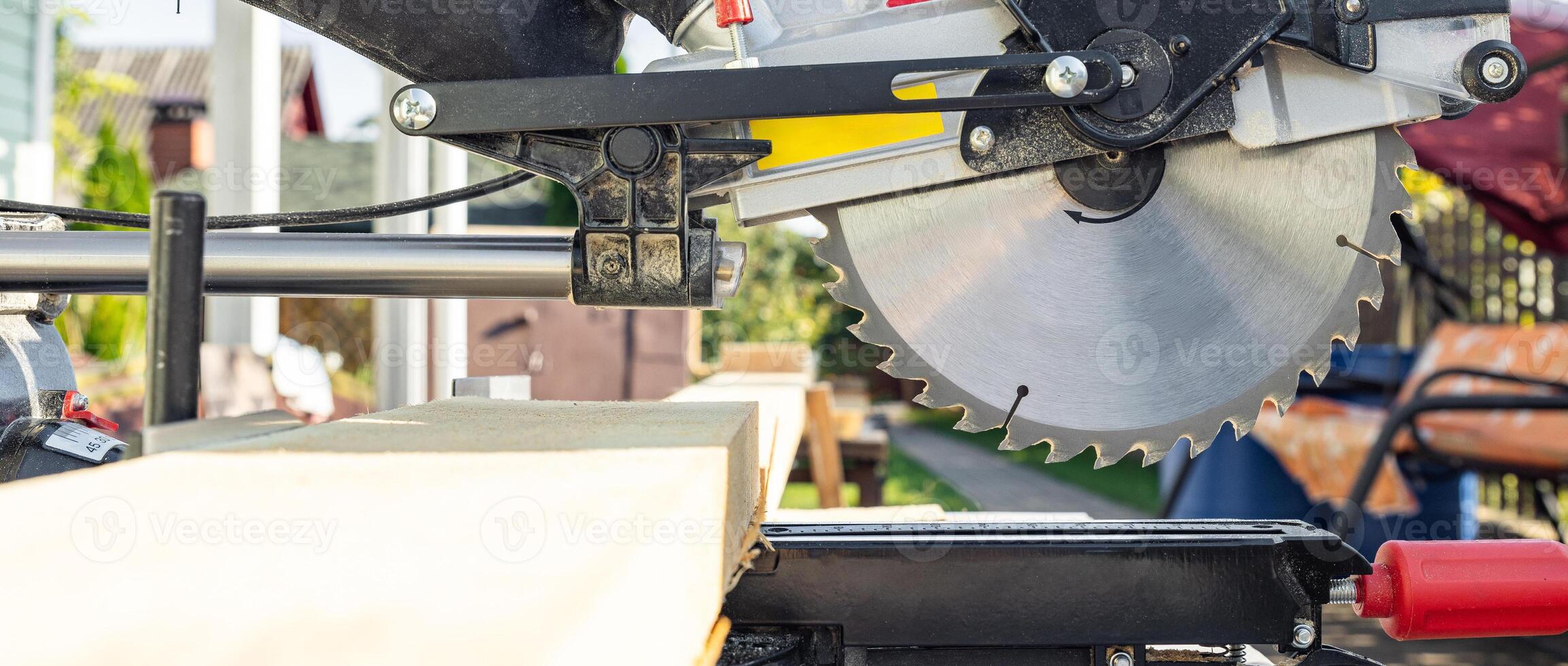 Cuts a wooden beam using a circular saw. Home furniture workshop. Work in his carpentry workshop. Miter saw and planks for building a house. photo