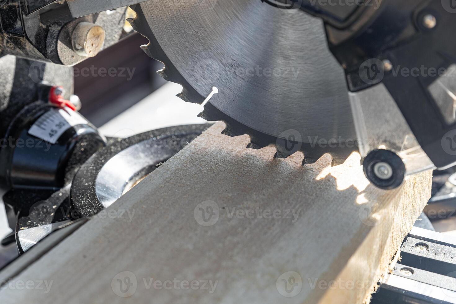 Using a miter saw to cut a piece of wood. Own carpentry workshop. Sawing a wooden board with a miter saw. Safe equipment for the furniture and construction industry. Close-up. photo