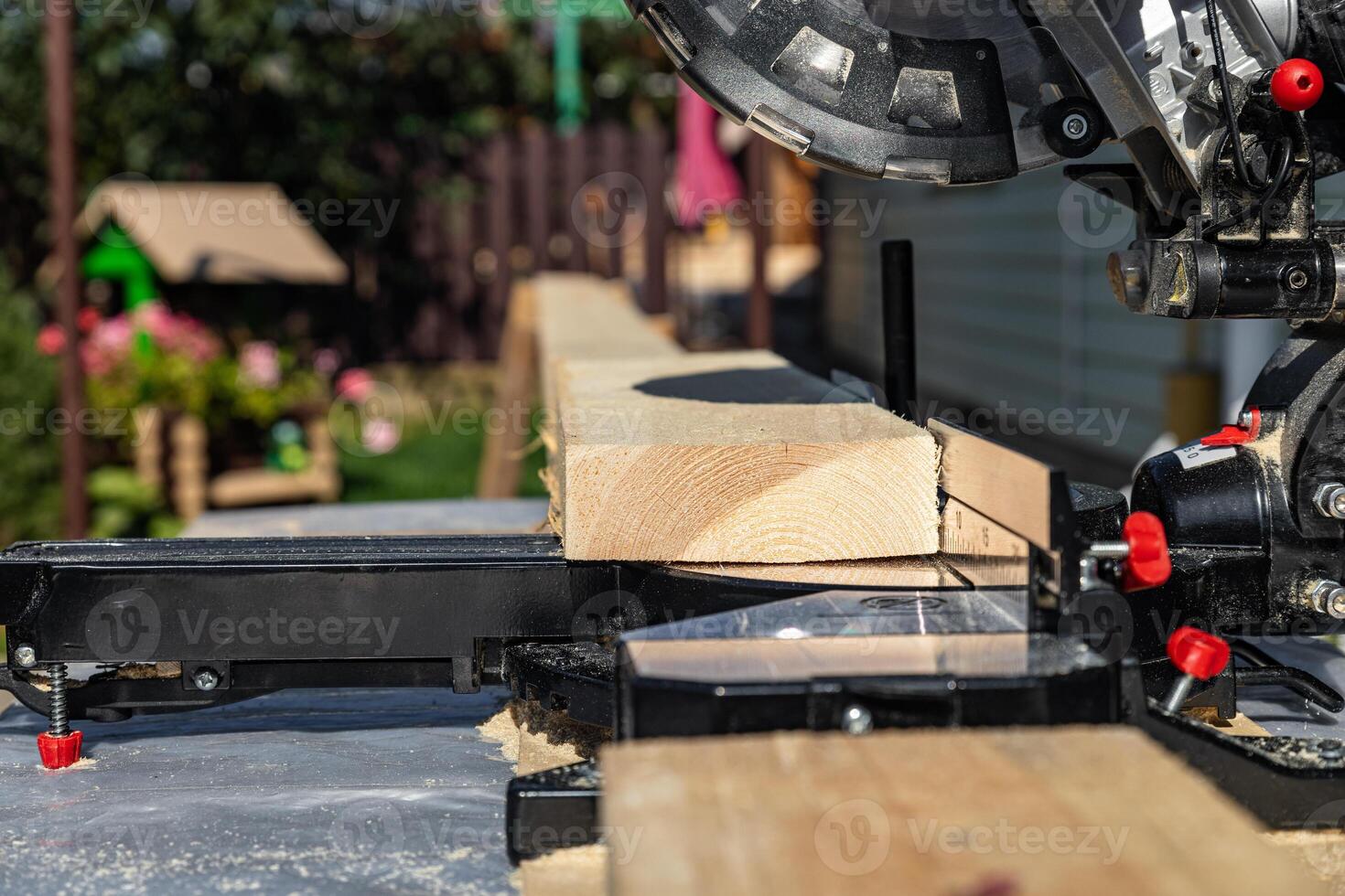Using a miter saw to cut a piece of wood. Own carpentry workshop. Sawing a wooden board with a miter saw. Safe equipment for the furniture and construction industry. Close-up. photo