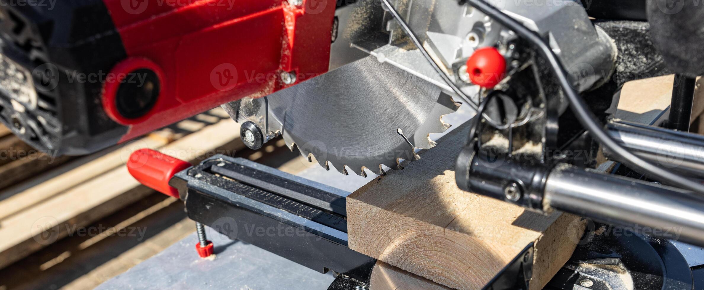 Cuts a wooden beam using a circular saw. Home furniture workshop. Work in his carpentry workshop. Miter saw and planks for building a house. photo