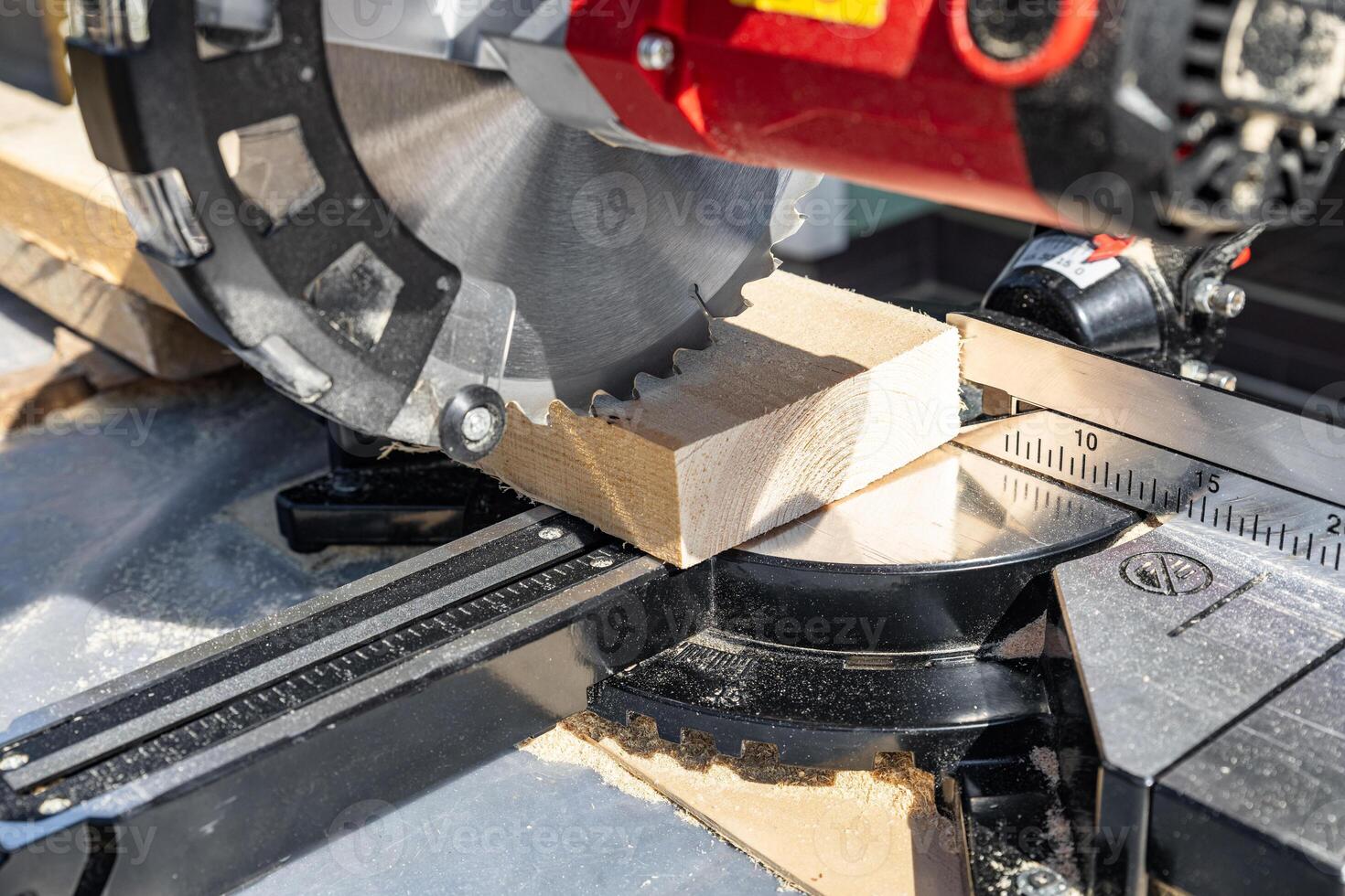 Using a miter saw to cut a piece of wood. Own carpentry workshop. Sawing a wooden board with a miter saw. Safe equipment for the furniture and construction industry. Close-up. photo