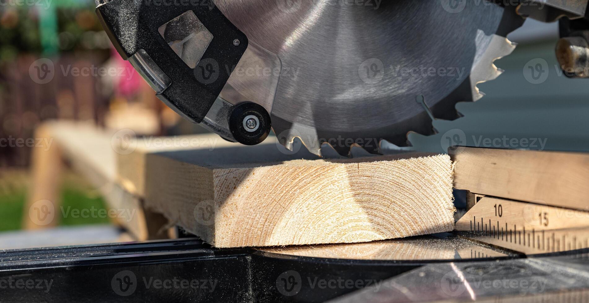 Using a miter saw to cut a piece of wood. Own carpentry workshop. Sawing a wooden board with a miter saw. Safe equipment for the furniture and construction industry. Close-up. photo