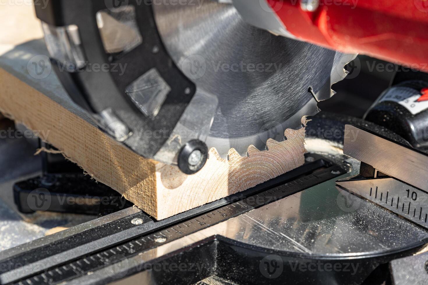 Using a miter saw to cut a piece of wood. Own carpentry workshop. Sawing a wooden board with a miter saw. Safe equipment for the furniture and construction industry. Close-up. photo