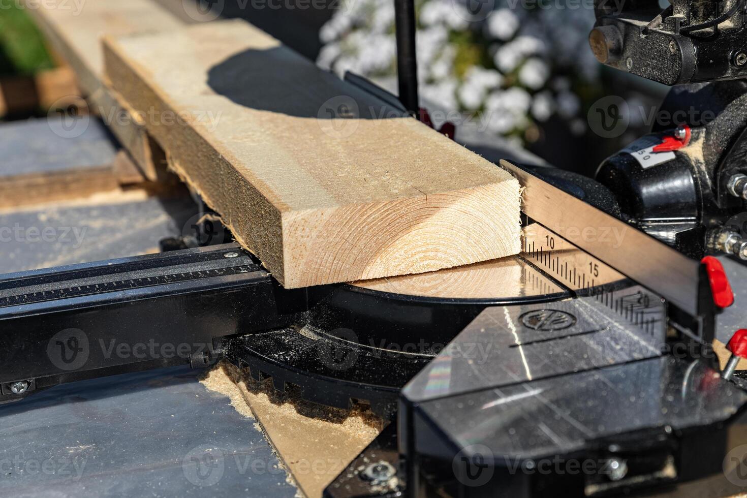 Using a miter saw to cut a piece of wood. Own carpentry workshop. Sawing a wooden board with a miter saw. Safe equipment for the furniture and construction industry. Close-up. photo