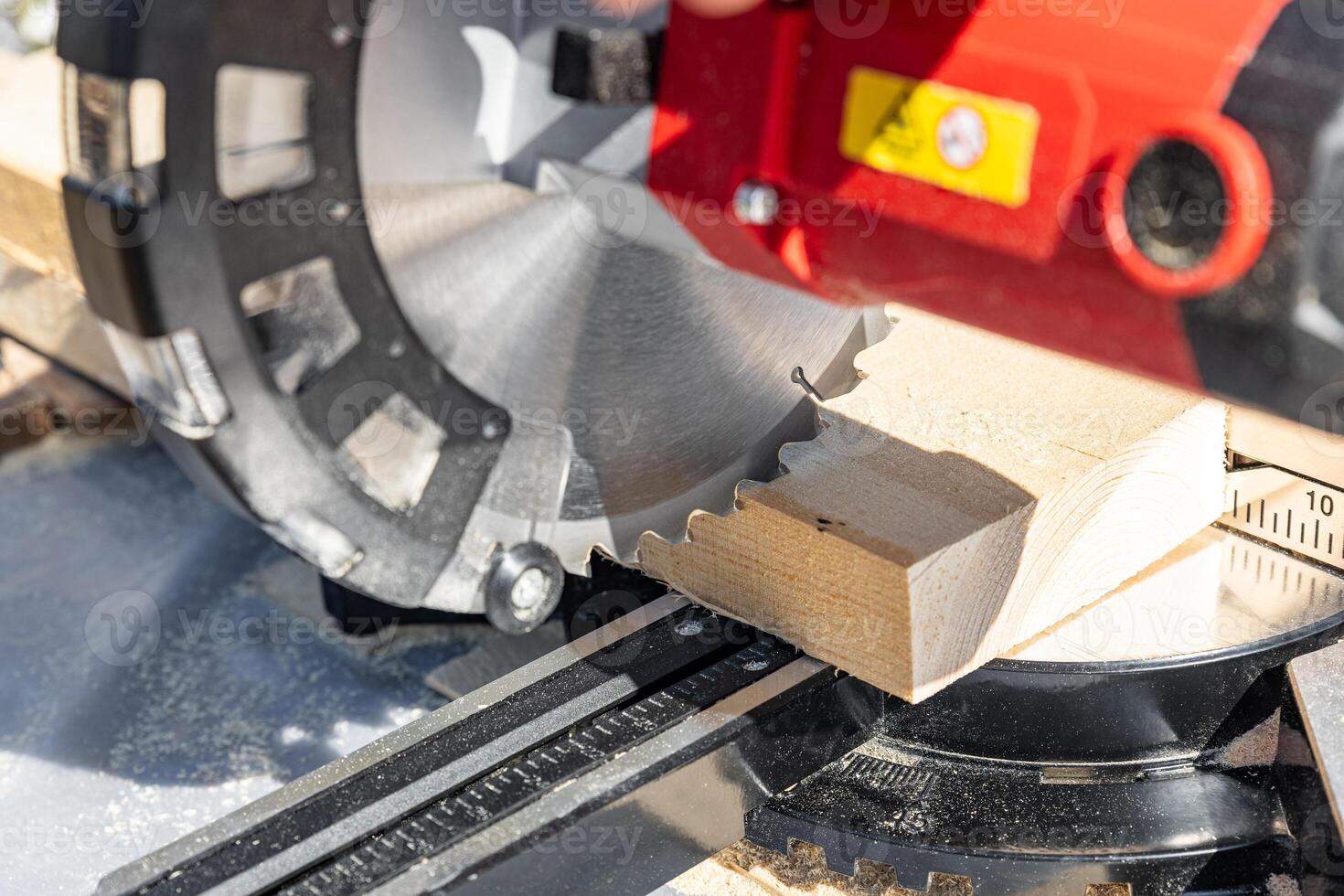 Using a miter saw to cut a piece of wood. Own carpentry workshop. Sawing a wooden board with a miter saw. Safe equipment for the furniture and construction industry. Close-up. photo