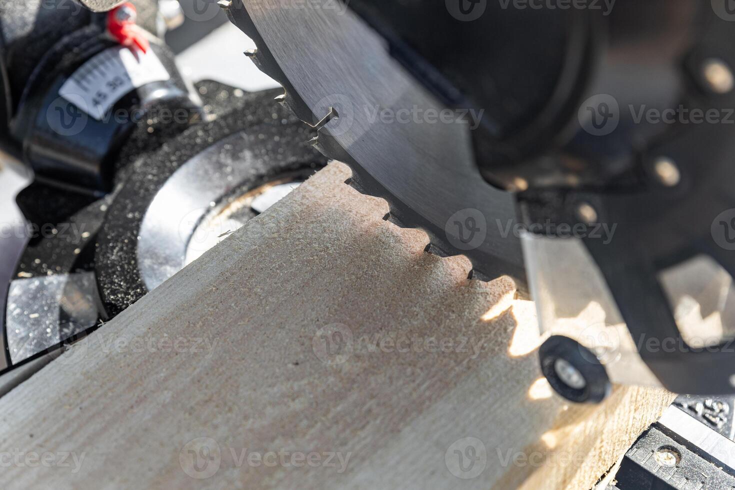 Using a miter saw to cut a piece of wood. Own carpentry workshop. Sawing a wooden board with a miter saw. Safe equipment for the furniture and construction industry. Close-up. photo