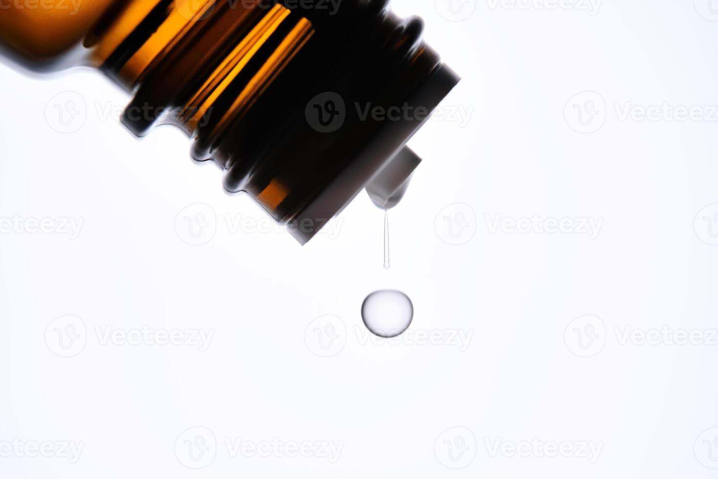 A drop of antihistamine or essential oil drips from a bottle. Close-up. photo