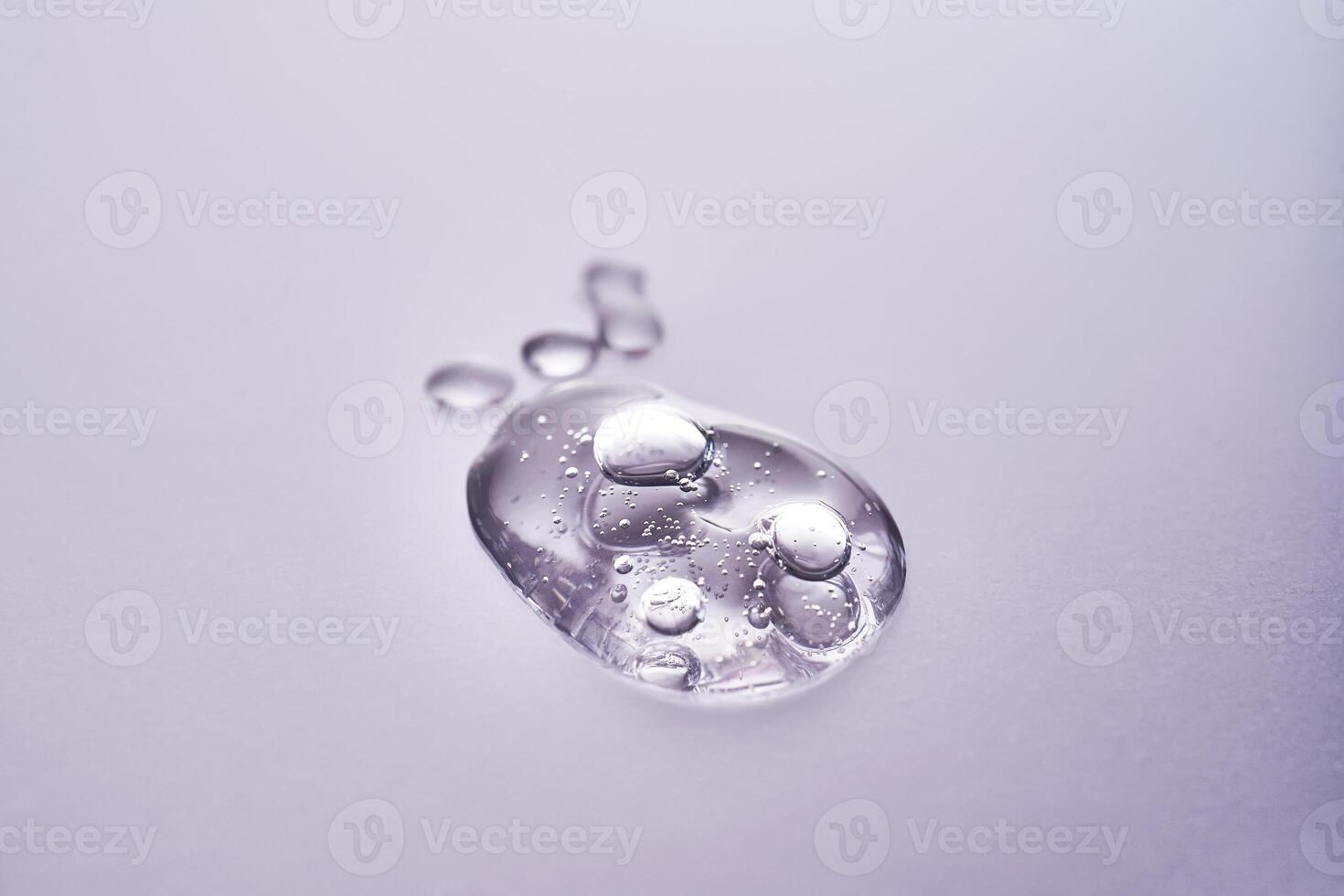 A drop of serum on a purple background. Texture of a cosmetic product. photo