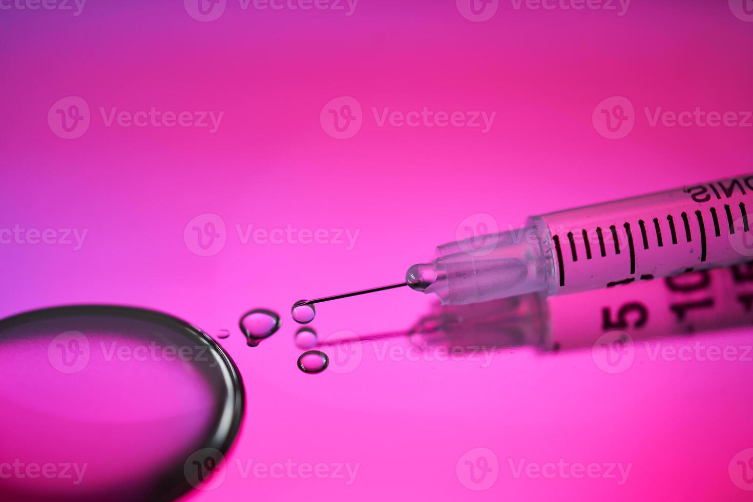 Injection syringe with a drop of drug on a rich pink background. photo