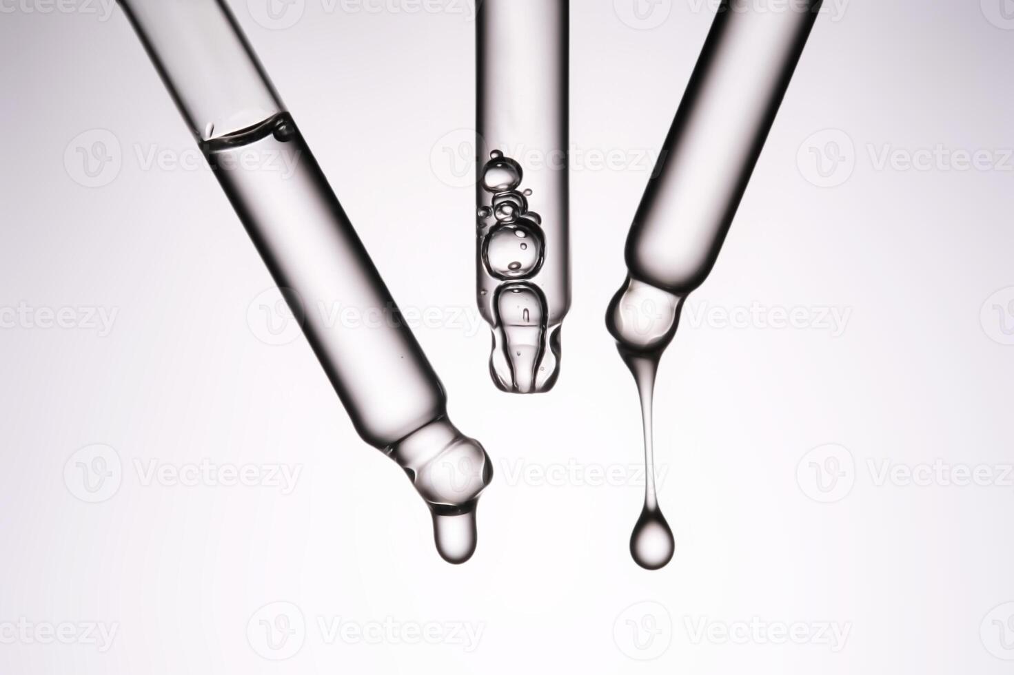 Three pipettes with a cosmetic product. Serum or fluid drips from one of them. photo