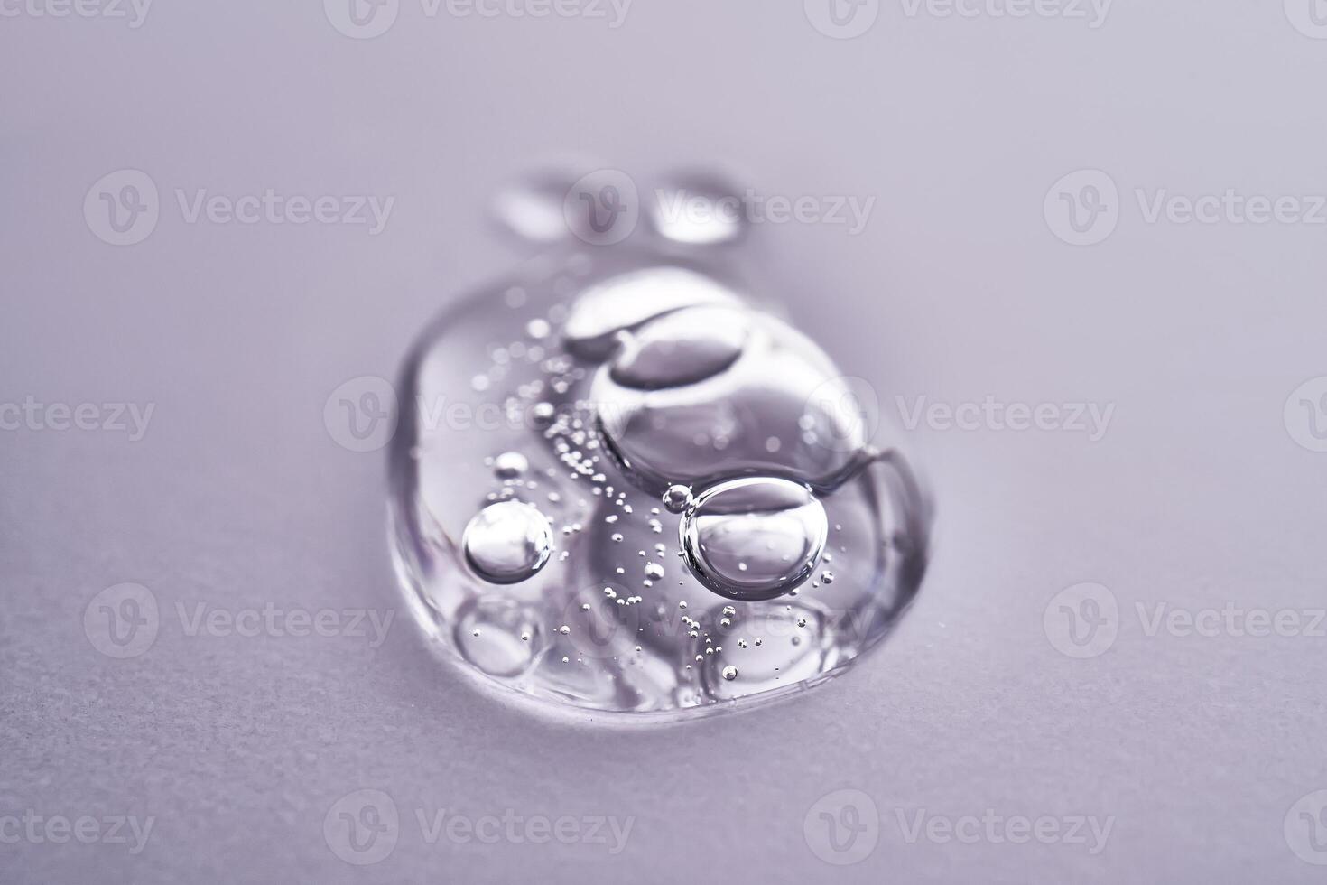 A drop of serum on a purple background. Texture of a cosmetic product. photo