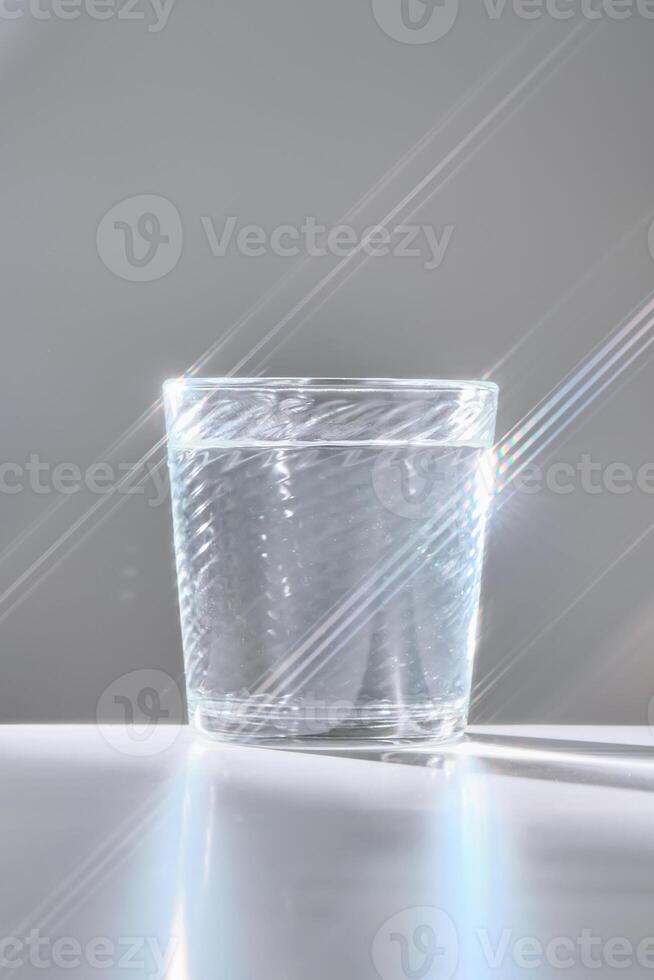 Glass of clean filtered water on white background with beautiful glare. photo