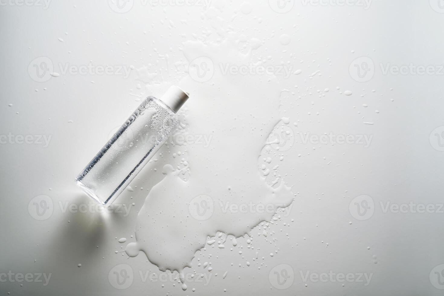 Bottle of facial toner or cleanser on white background with drops of product. photo