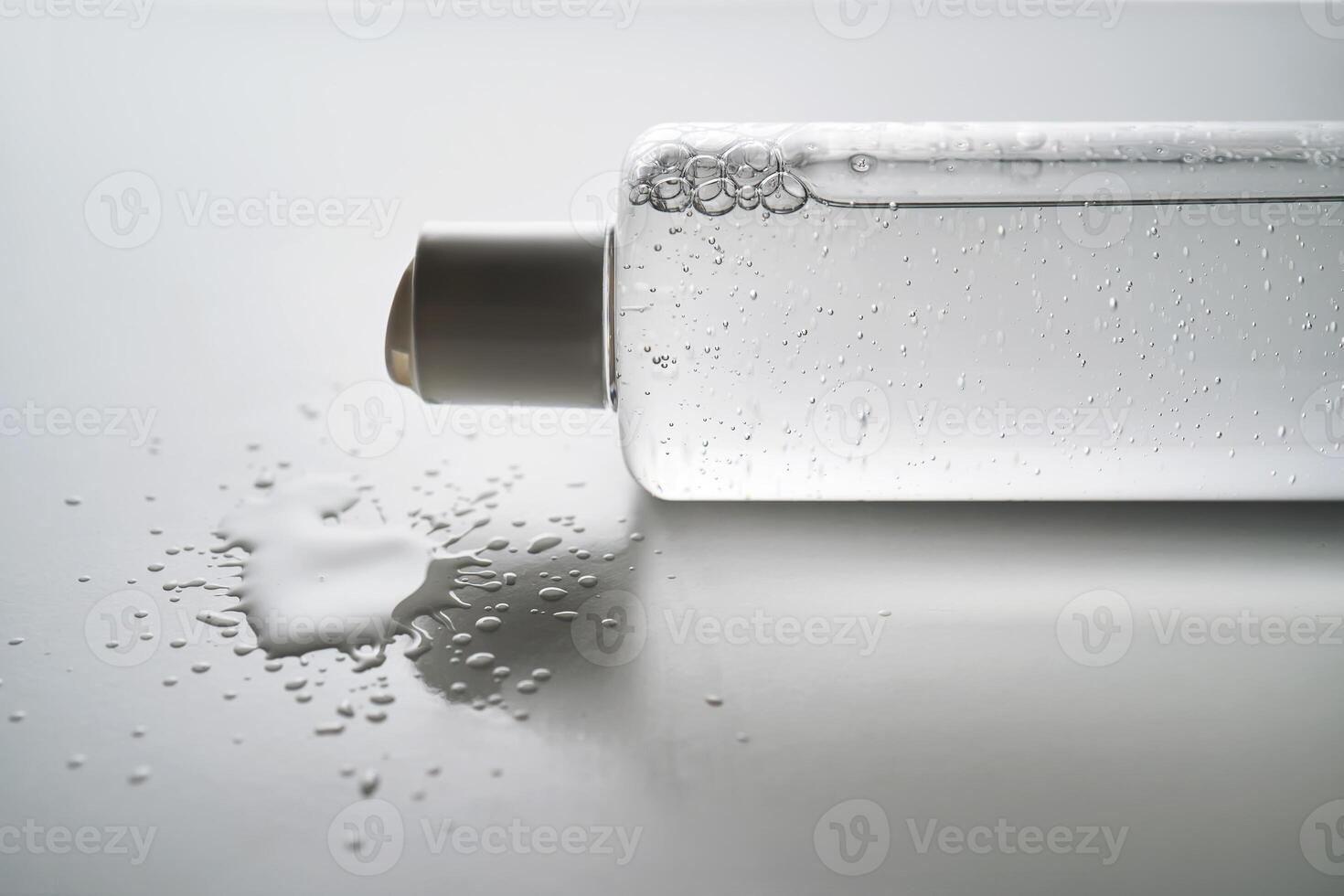 Bottle of facial toner or cleanser on white background with drops of product. photo
