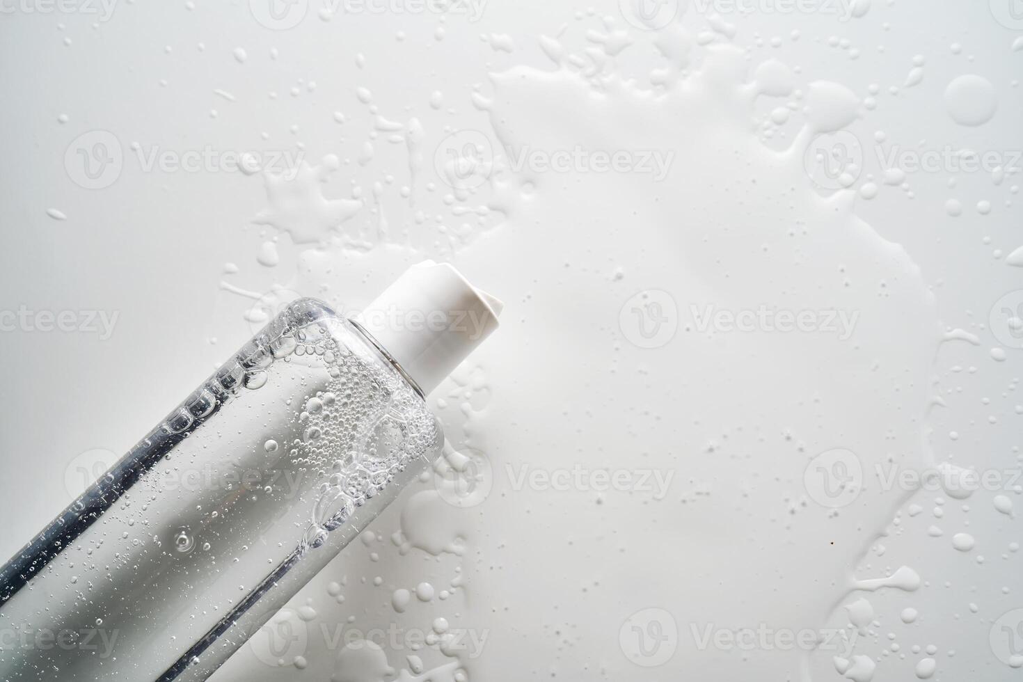 Bottle of facial toner or cleanser on white background with drops of product. photo