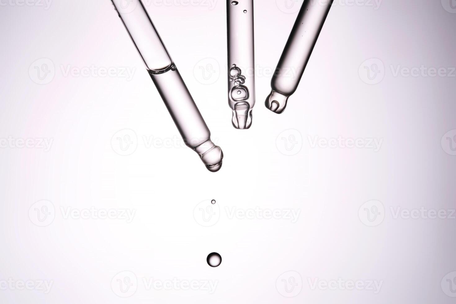 Three pipettes with a cosmetic product. Serum or fluid drips from one of them. photo