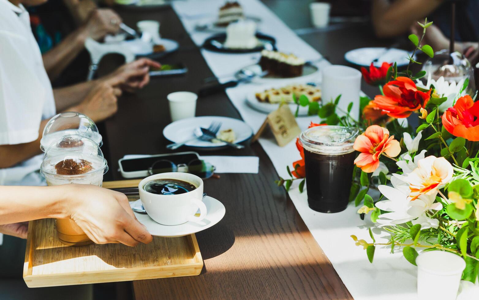 Waitress serving coffee drinks to group of friends meeting at cafe. photo