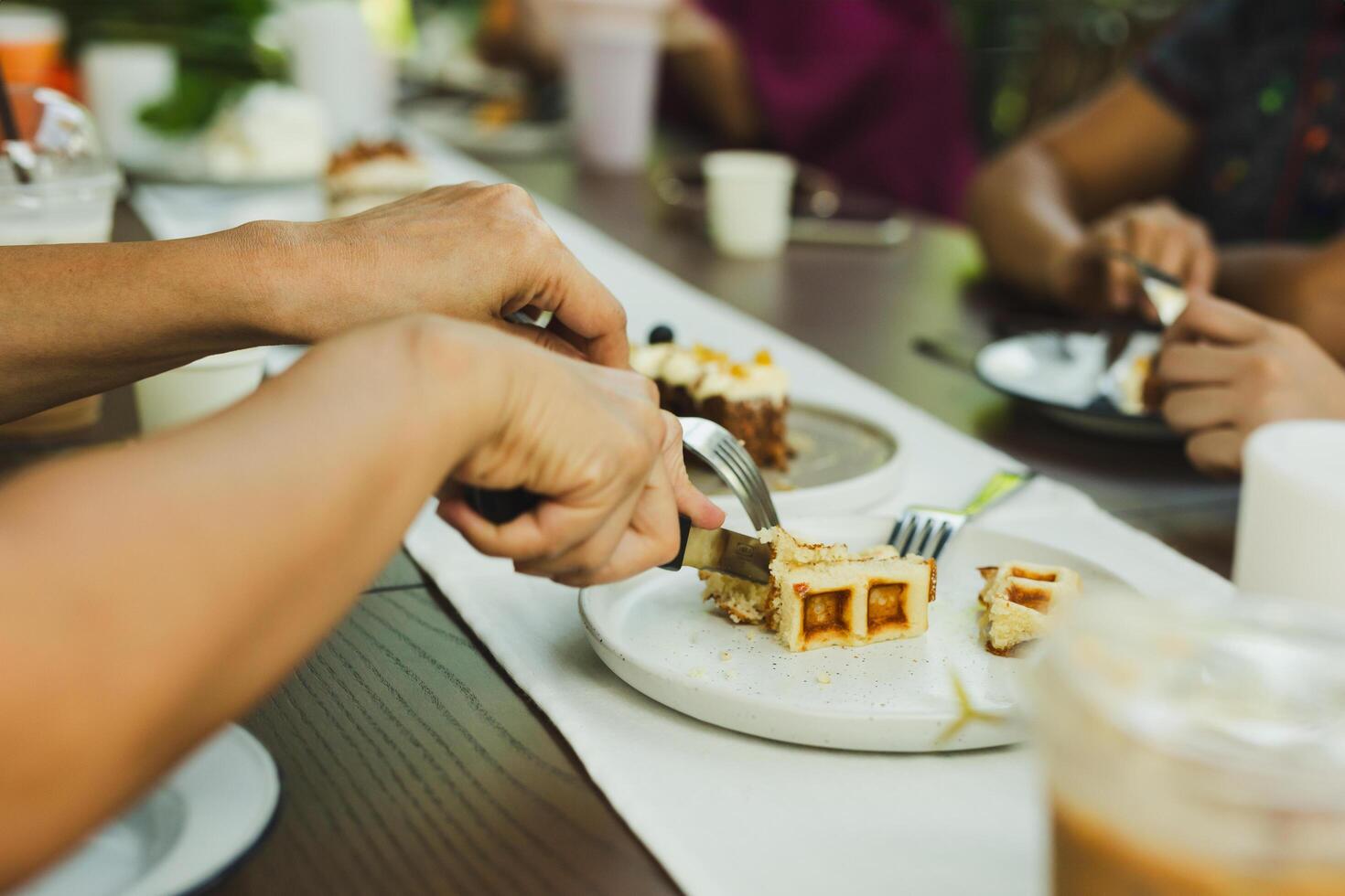 Woman hands cutting waffles with fork and knife on plate in cafe. photo