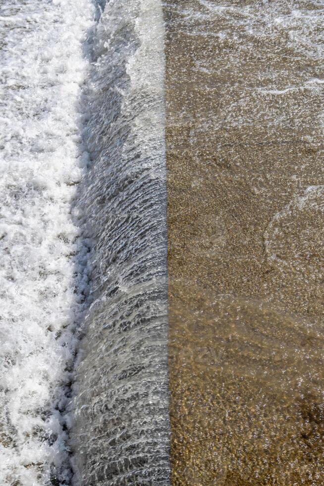 water falling from cascade edge of concrete water spillway channel photo