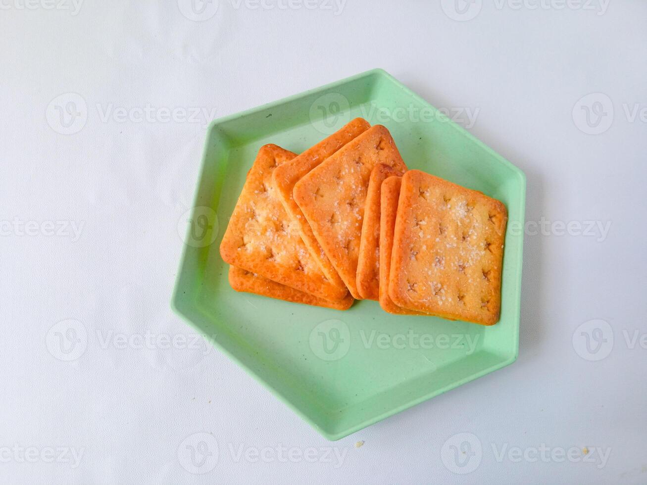 Sugar coated biscuits, also known as malkist, sweet and crispy. on a green hexagon plate isolate on white. snack concept photo