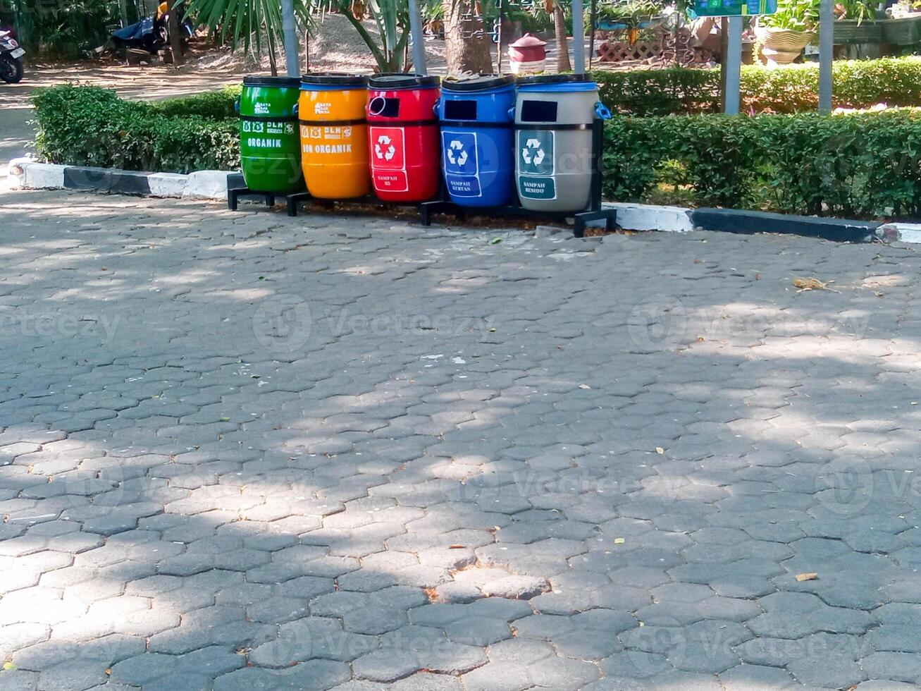 a red trash can for hazardous waste, yellow for non-organic waste, green for organic waste, which is placed in the city park. the concept of maintaining environmental cleanliness photo
