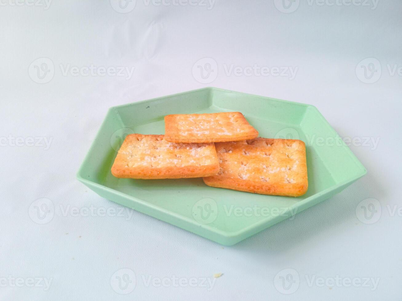 Sugar coated biscuits, also known as malkist, sweet and crispy. on a green hexagon plate isolate on white. snack concept photo