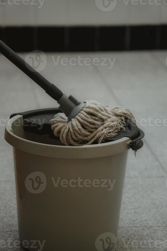 a bucket with a mop and a broom on a tile floor photo