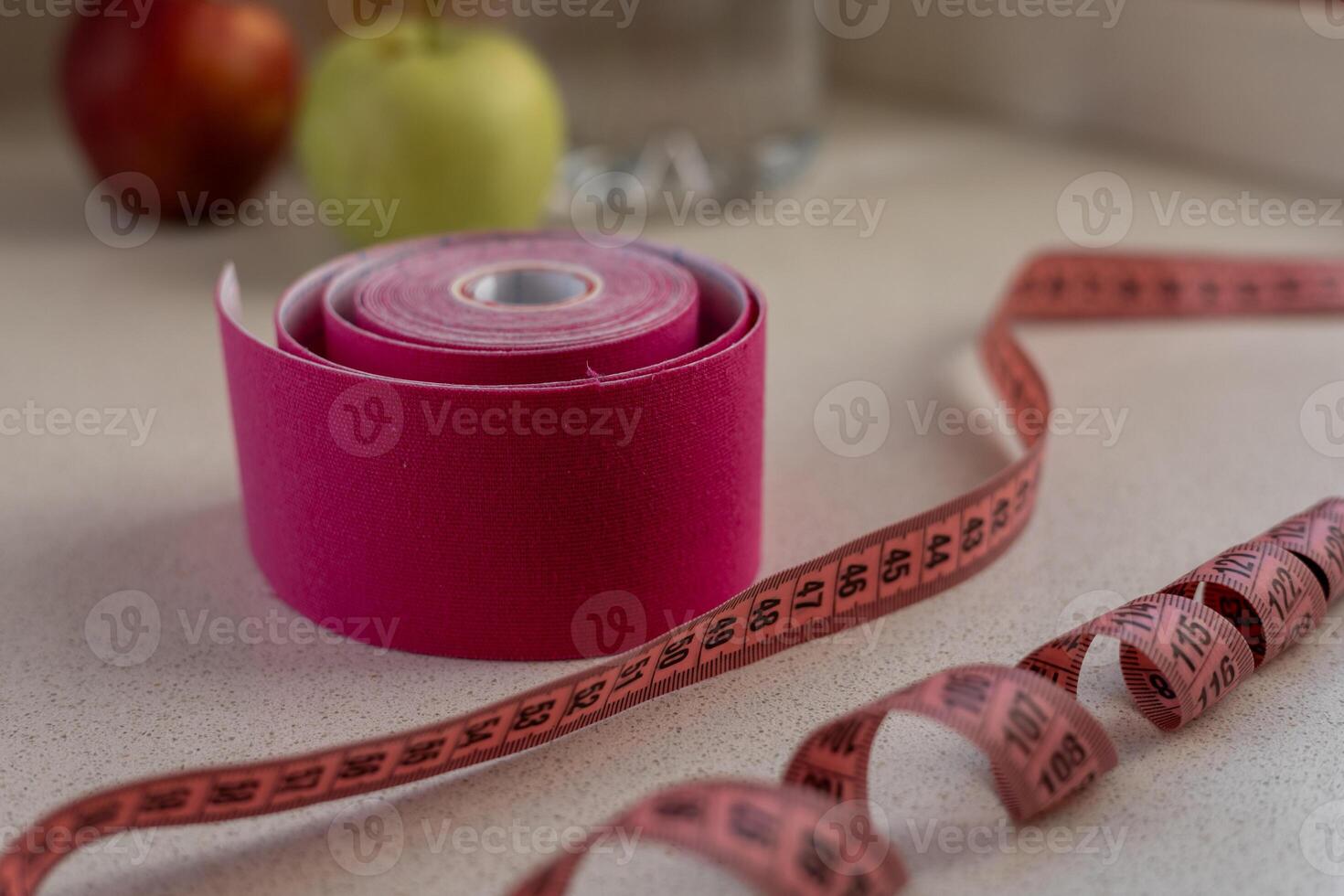 Pink kinesio tape with a measuring tape lying on a white background photo