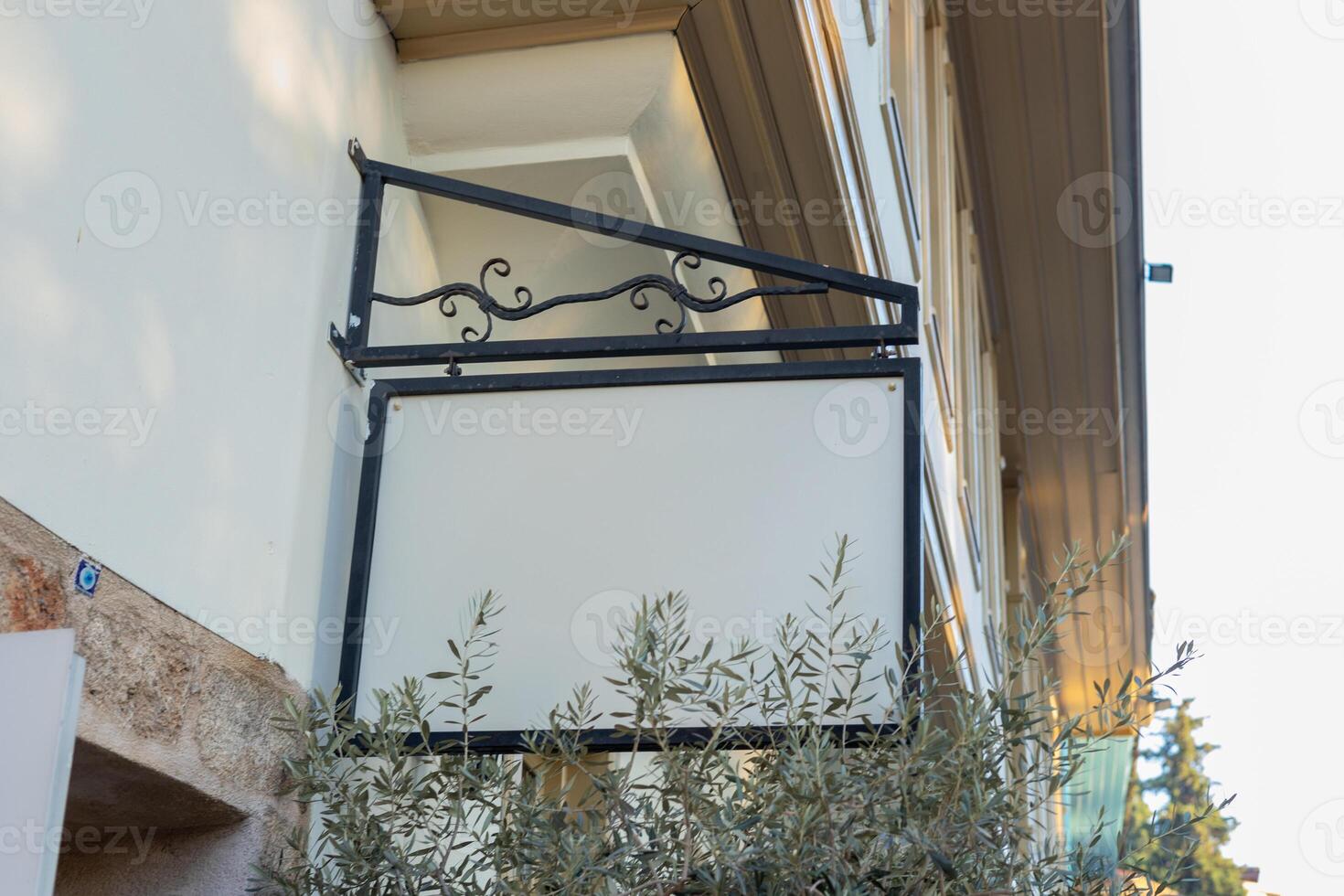 Blank sign hanging from a decorative bracket outside a building in a peaceful neighborhood photo