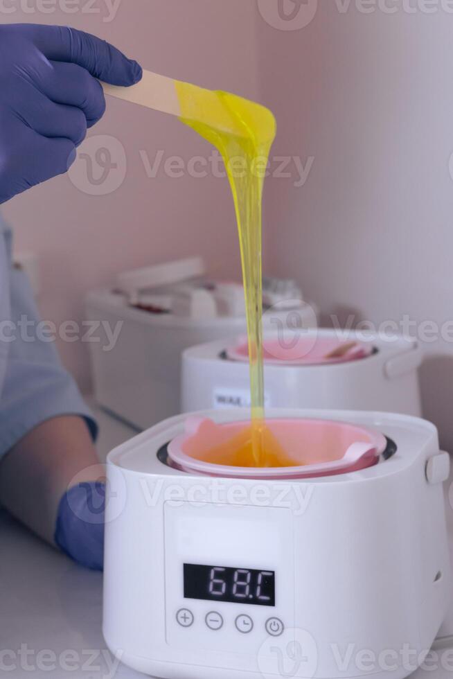 Waxing process in a beauty salon with warm wax and an applicator in use during daylight photo