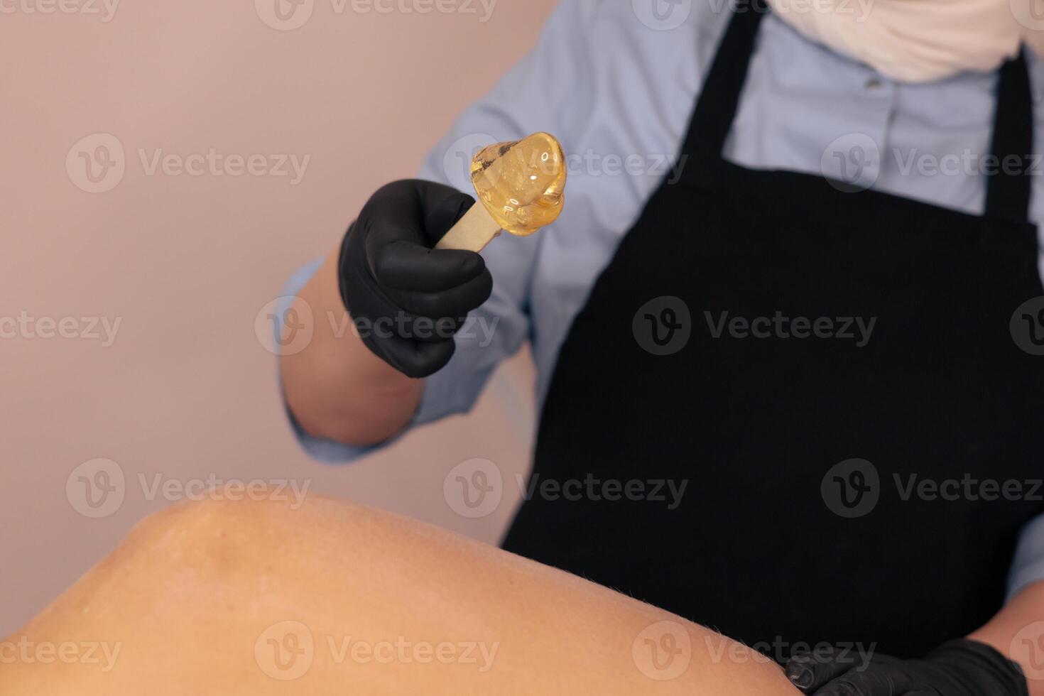 Waxing treatment being applied on a clients leg in a beauty salon during daylight hours photo