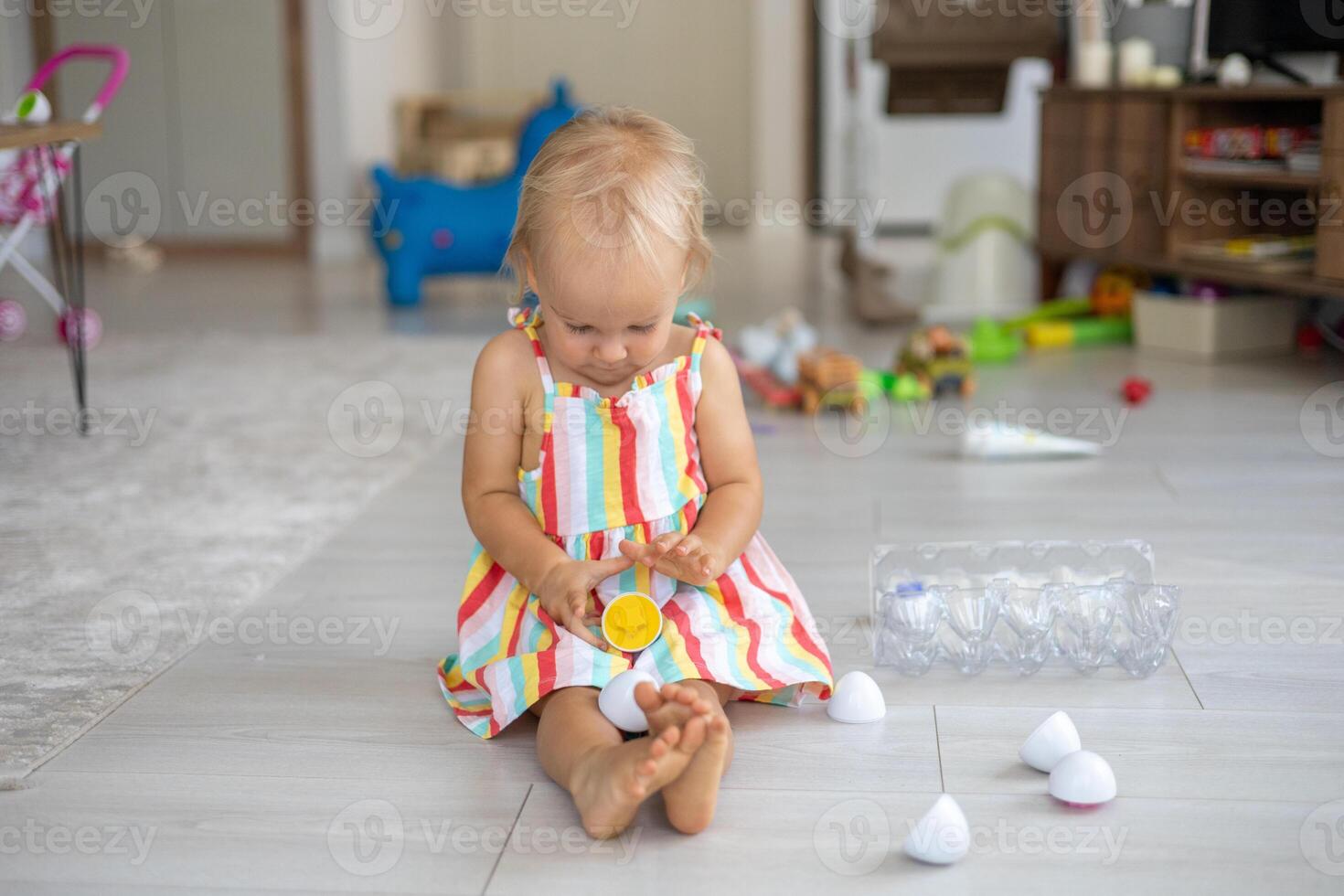 A beautiful blonde baby girl playing with a plastic montessori eggs photo